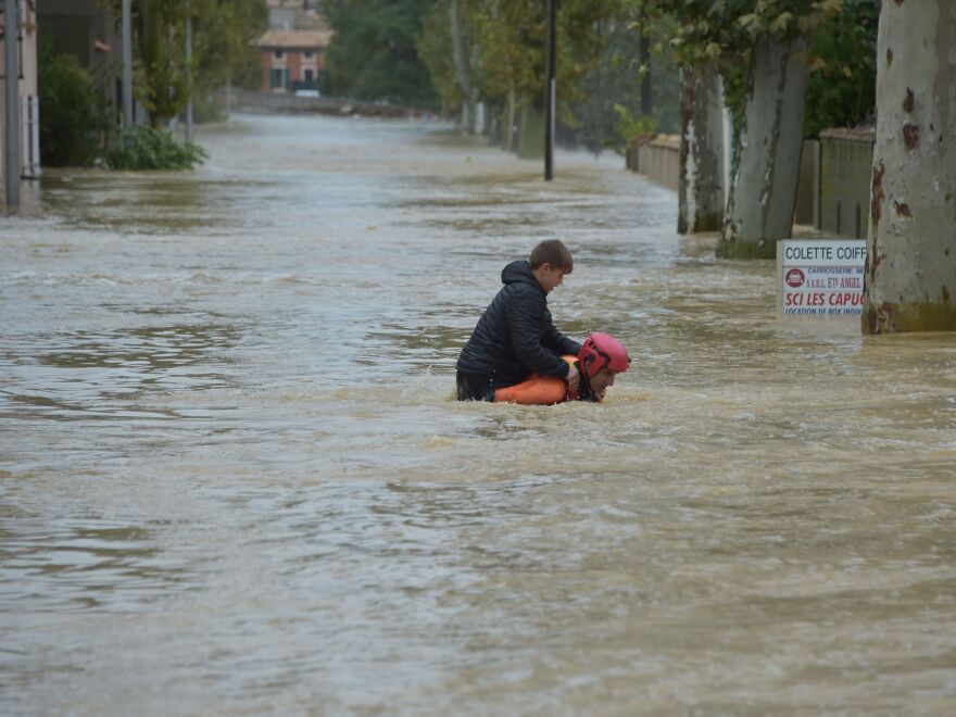 A firefighter helps a youngster reach safety in a flooded street during a rescue operation following heavy rains that saw rivers bursting their banks in Trèbes, near Carcassonne, in southern France.