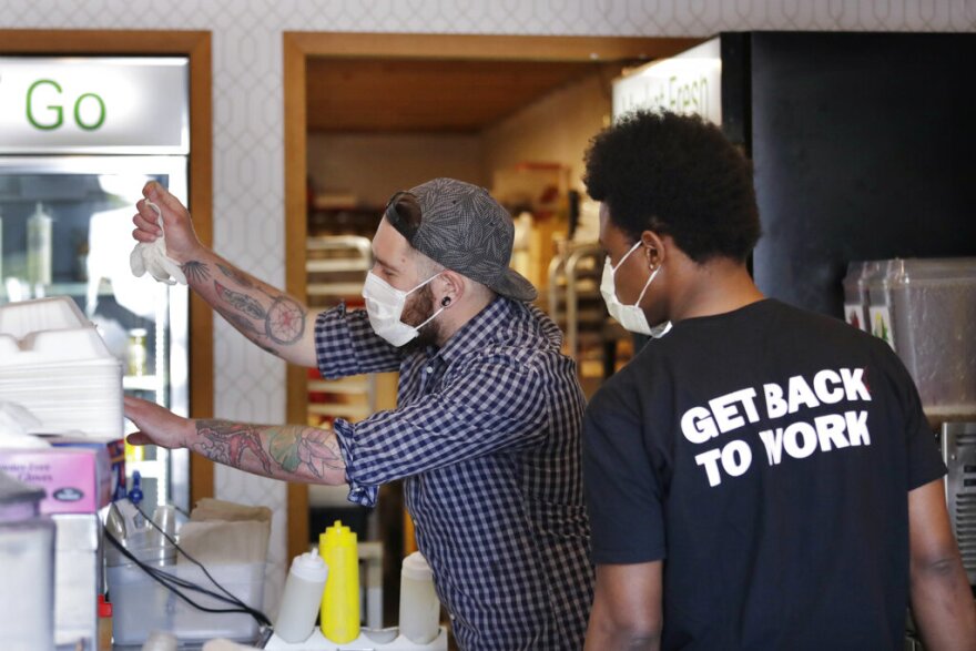 Falafel shop workers Bryant Movern, left, and Javohn Ferguson work to pack customer's take-out orders in a restaurant otherwise closed because of the coronavirus outbreak Tuesday, May 19, 2020, in Seattle.