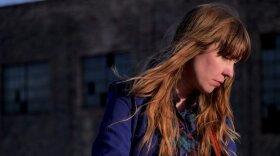 Folk artist Kelley Smith looks away while holding a guitar