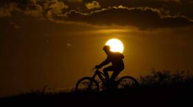 A cyclist tops a hill on a hot day at sunset in San Antonio. (Eric Gay/AP)