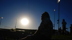 A baseball fan watches players warm up as temperatures hit 105-degrees prior to a spring training baseball game between the Los Angeles Dodgers and the San Diego Padres, Friday, March 20, 2026, in Phoenix. (AP Photo/Ross D. Franklin)