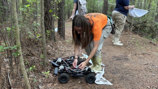 ODU master's student Willow Baker sets up a 'TickBot' prototype on a neighborhood trail in Chesapeake on July 27, 2026.