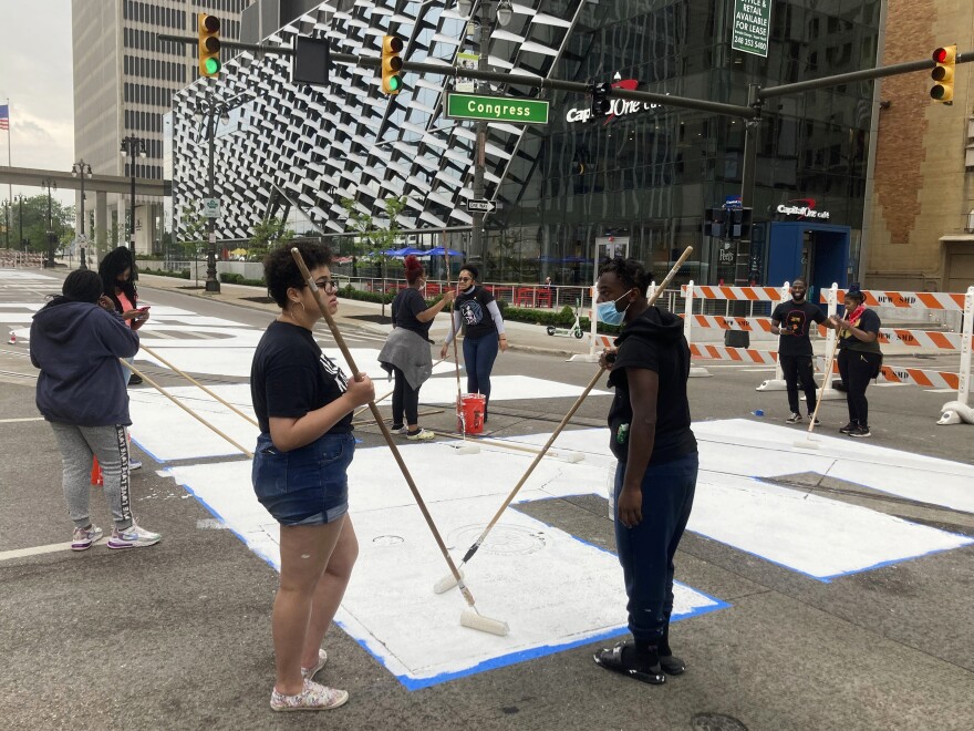 A mural displaying the words "Power To The People" is repainted in honor of Juneteenth by students studying at the University Prep Art Design. The mural was first painted last year for the holiday.