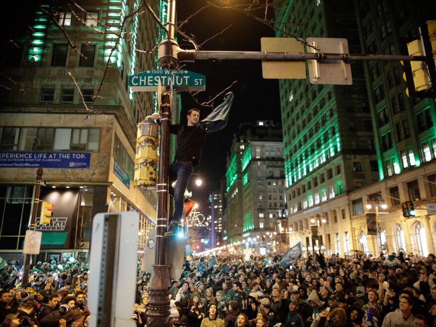 A man climbs a traffic pole as Philadelphia Eagles fans celebrate victory in Super Bowl LII against the New England Patriots Sunday evening.