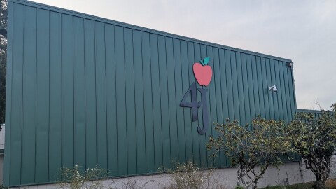 A green outdoor wall with 4J apple logo.