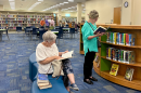 Martha Camp, left, and Pat Dixon browse through books during the grand opening of Freedom Public Library. The reopening drew community members eager to explore the expanded space. (Ornella Moreno/WUFT News)