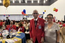Daniel Keel, a 104-year-old Tuskegee veteran, poses with his daughter. He wears a red blazer. 