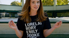 Generation Gilmore Girls podcast host Chloe Wynne sitting on the steps of the Milford town green gazebo. 