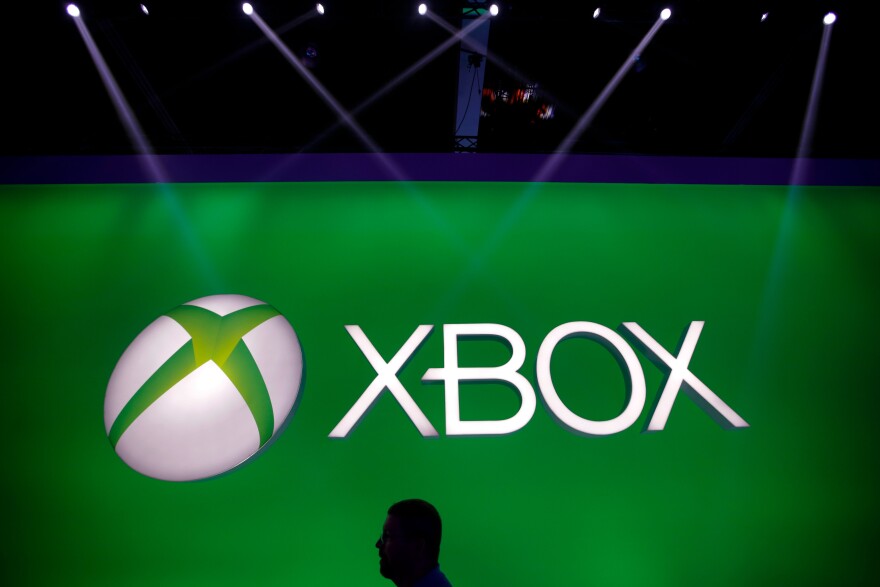 A man walks past the Xbox logo at the Microsoft booth during the E3 game show in Los Angeles, Tuesday, June 11, 2013.