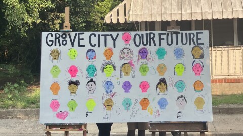 A large canvas with an array of faces painted on in every color of the rainbow reads, "Groove City, our future".