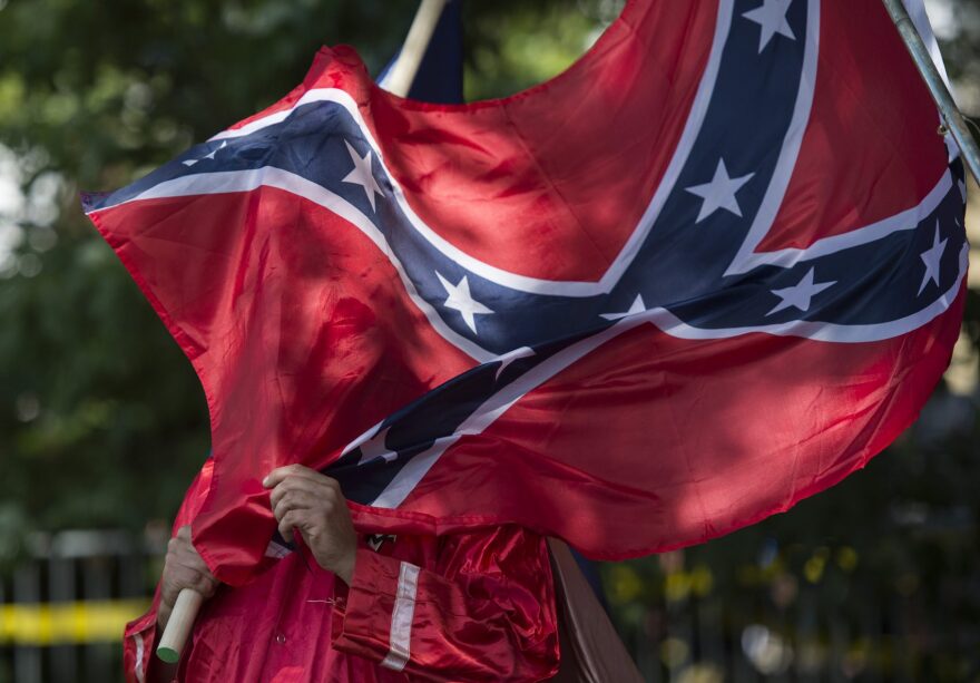 A member of the Ku Klux Klan holds a Confederate flag over his face during a rally, calling for the protection of Southern Confederate monuments, in Charlottesville, Va., on July 8, 2017. (Andrew Caballero-Reynolds/AFP/Getty Images)