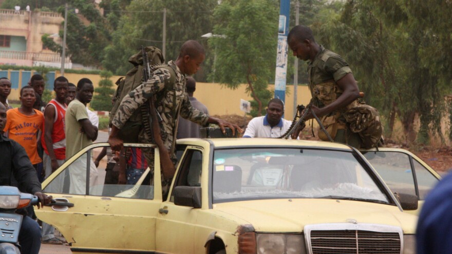 Soldiers loyal to junta leaders in Mali load their weapons, including a machine gun, onto a taxi after leaving a military camp where anti-junta forces were subdued.