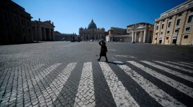 A woman walks across a deserted Pope Pius XII square in Rome, near the Vatican's St. Peter's Square (Rear) during the lockdown.