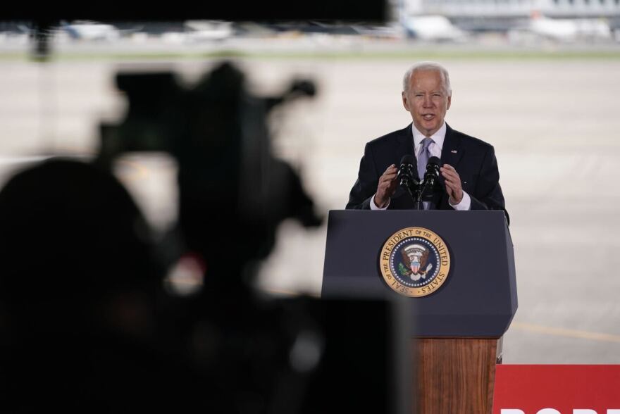 President Joe Biden addresses a camera while standing behind a podium on the tarmac at the Portland Airport.