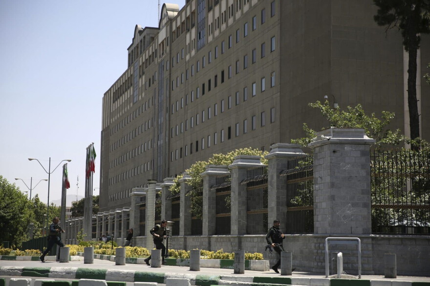 Police officers run to take position around Iran's parliament building after an assault of several attackers, in Tehran, Iran, Wednesday, June 7, 2017. Several attackers stormed into Iran's parliament and a suicide bomber targeted the shrine of Ayatollah Ruhollah Khomeini on Wednesday, killing a security guard and wounding 12 other people in rare twin attacks, with the shooting at the legislature still underway. (Fars News Agency, Ali Khara via AP)