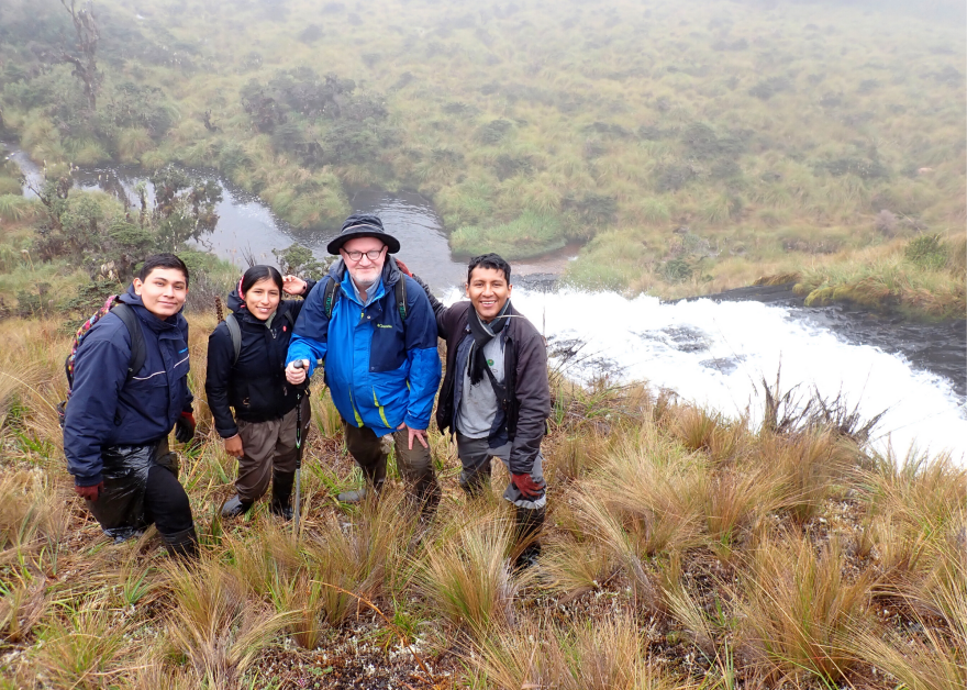 Four people in jackets posing for a photo from a mountainside