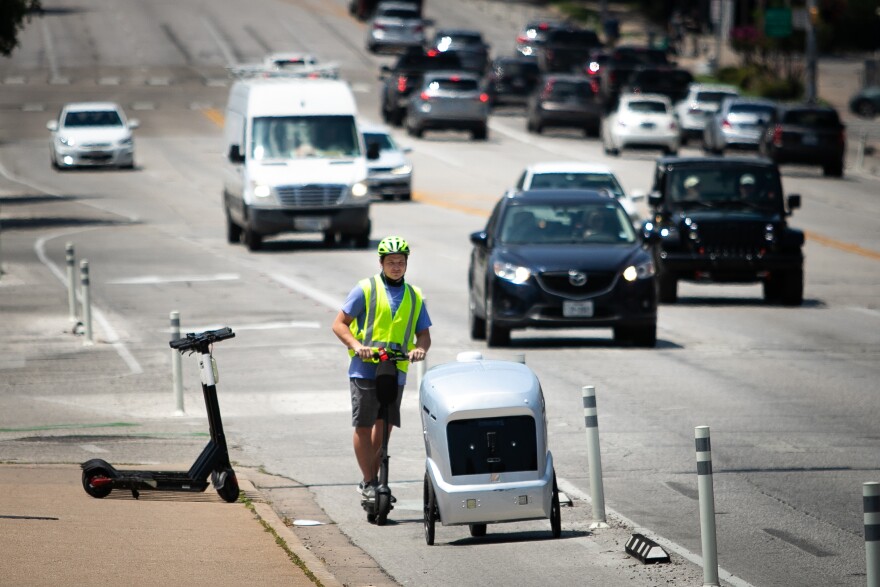 Riley Pakes, integrante de la compañía robótica Refraction AI, monitorea el desempeño de un robot de entregas a domicilio que viaja por el centro de Austin el 16 de junio.