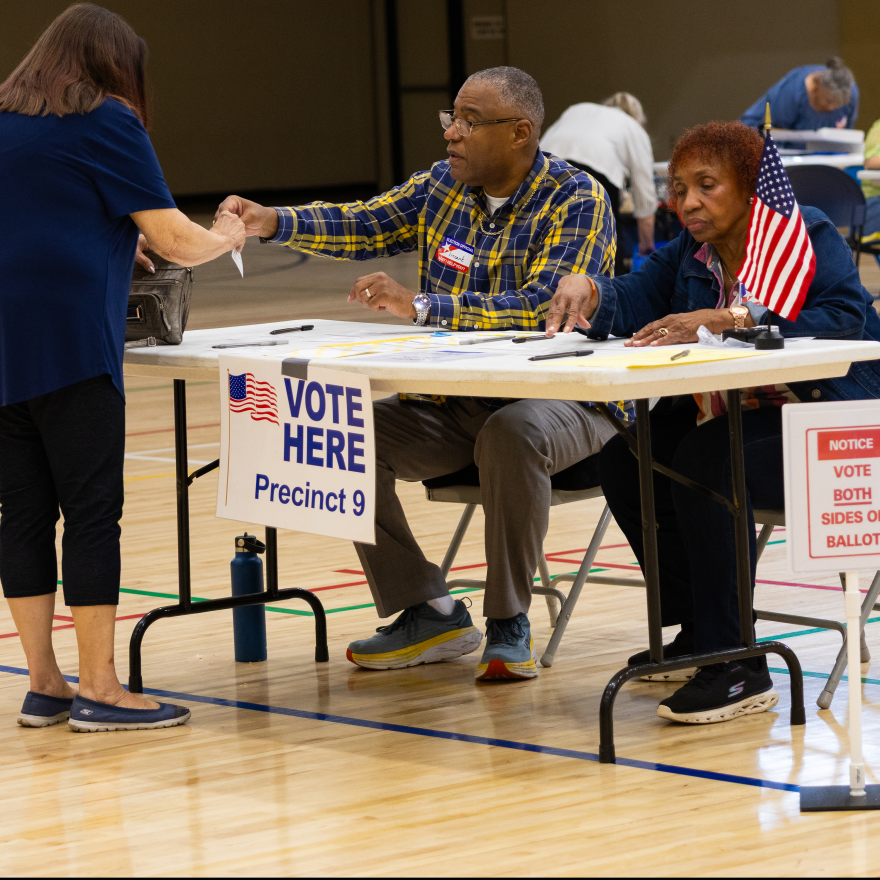 Saginaw Township poll workers Vincent McMillon and May Wathen help a voter prepare to cast her ballot in the Aug. 4, 2026 primary election.