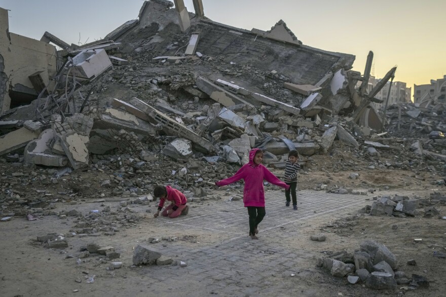 FILE - Palestinian children play next to a building destroyed by Israeli army strikes in the central Gaza Strip town of Khan Younis, Jan. 1, 2025. (AP Photo/Abdel Kareem Hana, File)