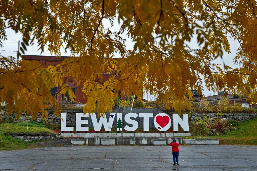 A man photographs a make-shift memorial at the base of the Lewiston sign at Veteran's Memorial Park, Oct. 29, 2023, in Lewiston, Maine.