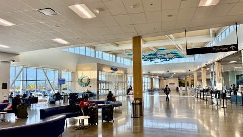 A wide shot of the terminal at the Columbia Regional Airport. Half a dozen passengers lounge on couches with their luggage nearby. 