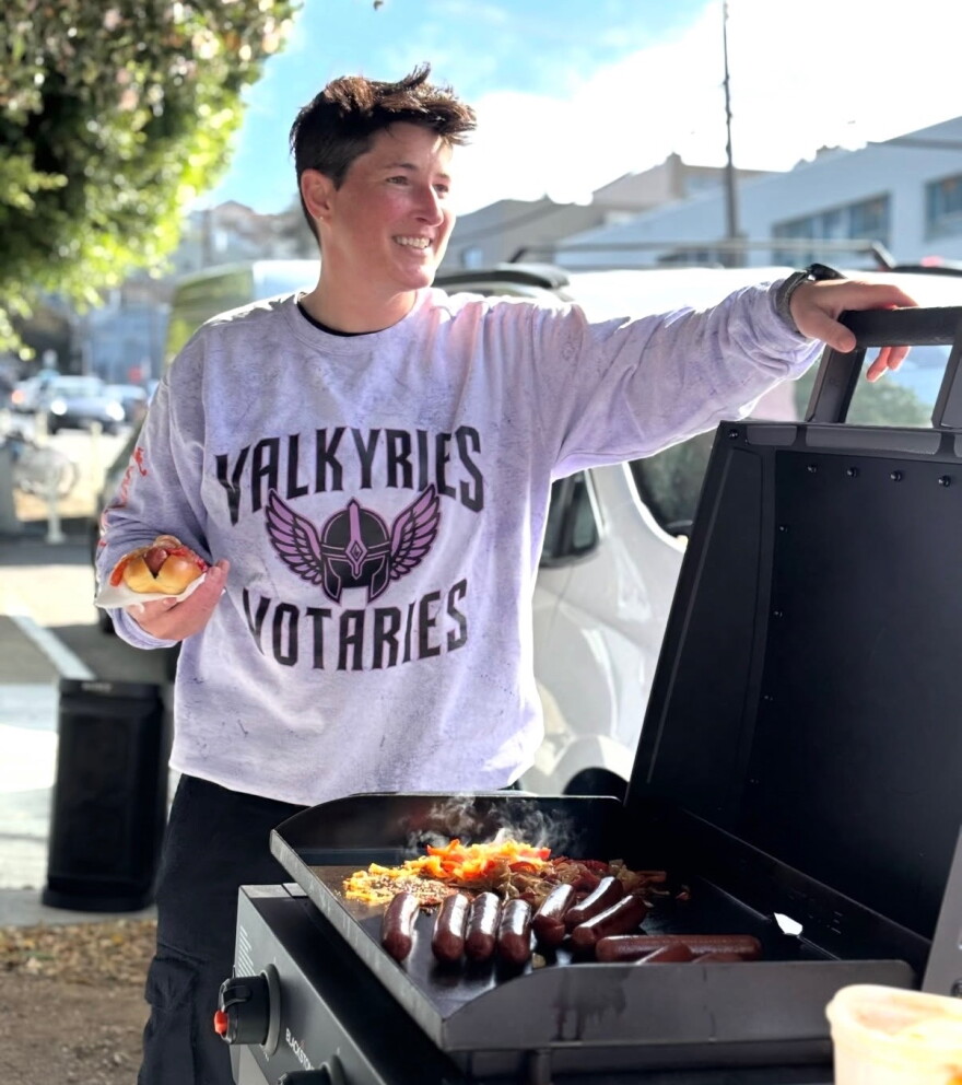 Natasha Dantzing serves up a free hot dog with onions and peppers at a tailgate party she and her wife organized before the Valkyries' first playoff home game on September 27, 2026.
