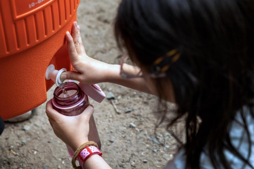 A camper fills up her water bottle at an ice-water filling station at Hale Day Camp.  (Robin Lubbock/WBUR)
