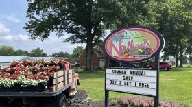 Northgate Greenhouses' sign sits in a flower bed, next to a pickup truck filled with flowers. 