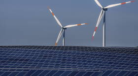 Wind turbines turn behind a solar farm in Rapshagen, Germany, Thursday, Oct. 28, 2021.
