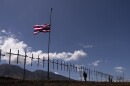 Crosses honoring the victims killed in a recent wildfire hang on a fence along the Lahaina Bypass as a Hawaiian flag flutters in the wind in Lahaina, Hawaii, Tuesday, Aug. 22, 2023. Two weeks after the deadliest U.S. wildfire in more than a century swept through the Maui community of Lahaina, authorities say anywhere between 500 and 1,000 people remain unaccounted for. (AP Photo/Jae C. Hong)