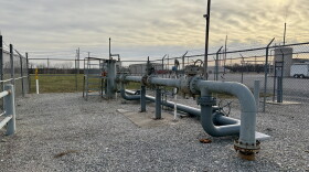 Metal pipes outside a gas plant go into the ground and connect to each other above ground. 