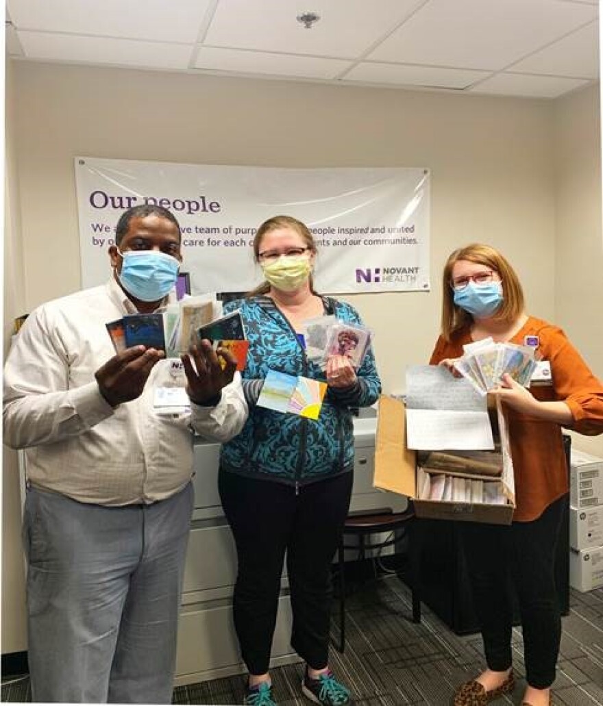 Novant Health chaplains Chris Williams, Lisa Huffman and Chelsy Mitchell hold up artwork they received as part of the project.