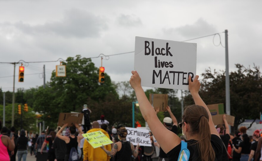 woman holding a sign that says "black lives matter"