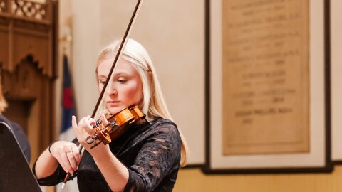 A picture of local musician Meredith Crifasi playing violin. She is wearing all black. 