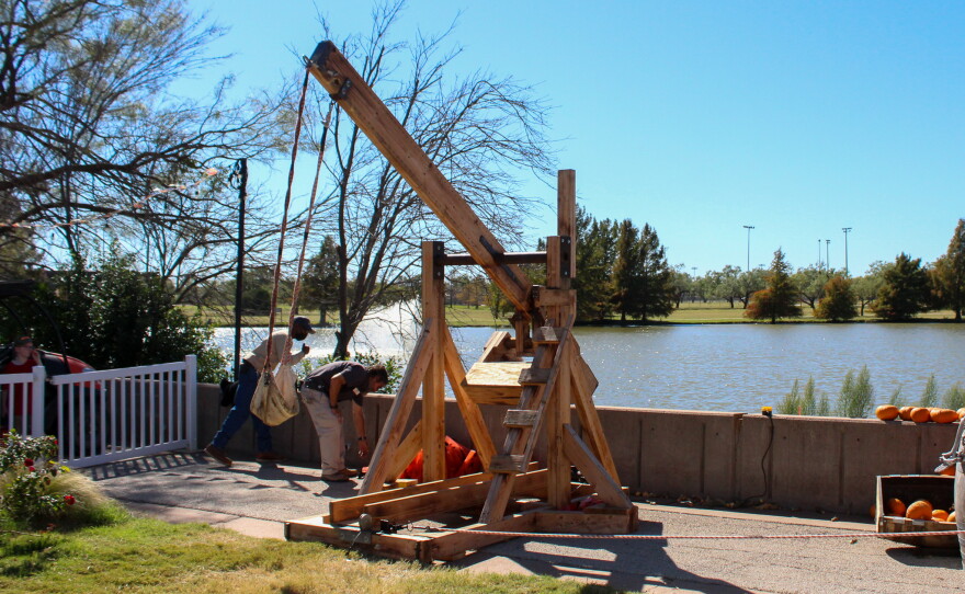 A wooden catapult launches pumpkins into the lake.