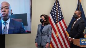 Gov. Kathy Hochul and Lt. Gov. Brian Benjamin look at a wall monitor with New York City Mayor Eric Adams on it.