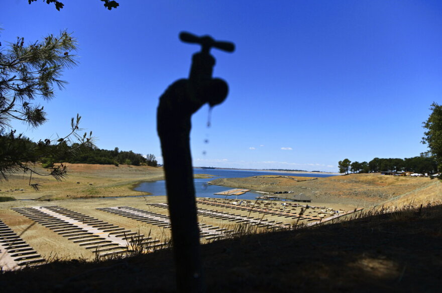 FILE - Water drips from a faucet near boat docks sitting on dry land at the Browns Ravine Cove area of drought-stricken Folsom Lake, in Folsom, Calif., on May 22, 2021. The sight of fountains, swimming pools, gardens and golf courses in Western cities like Phoenix, Los Angeles, Las Vegas, San Diego and Albuquerque can seem jarring with drought and climate change tightening their grip on the region. But Western water experts say they aren’t necessarily cause for concern. Many Western cities over the past three decades have diversified their water sources, boosted local supplies, and use water more efficiently now than in the past.(AP Photo/Josh Edelson, File)
