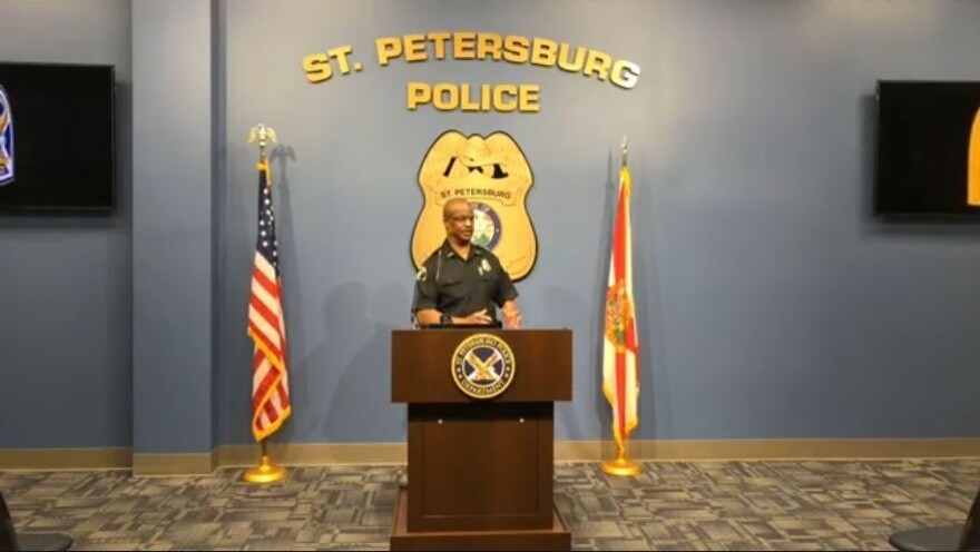 police officer stands a podium between American and Florida flags