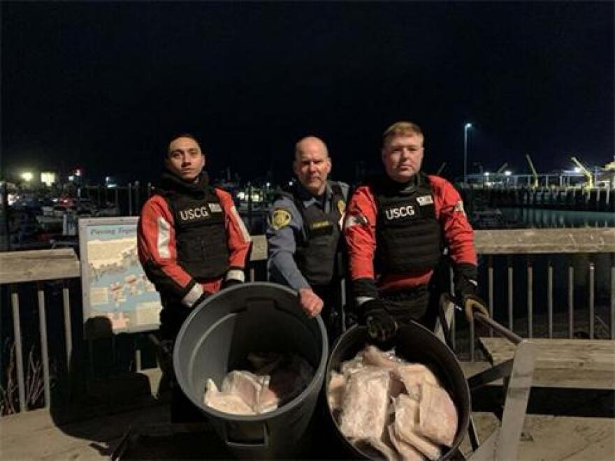 Two crewmembers from Coast Guard Cutter Naushon and a member from the National Oceanic and Atmospheric Administration Office of Law Enforcement (NOAA OLE) pose for a picture with allegedly illegally-retained halibut in Homer on Nov. 30, 2022.