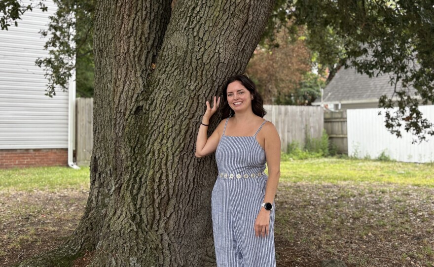 Elizabeth Burrows stands with a live oak tree on a vacant lot next to her home in Norfolk's Park Place, on June 16, 2026.