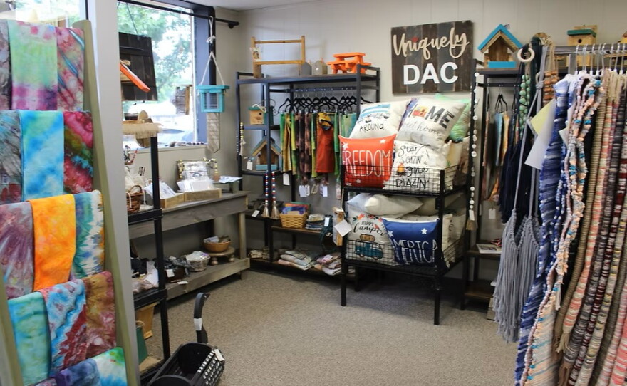 A cozy corner of a thrift store with tie-dyed items, handmade rugs, pillows and more. 
