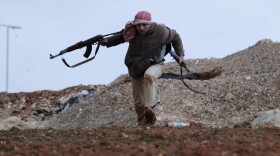 A Syrian rebel runs for cover during an exchange of fire with army troops in Idlib, Syria.