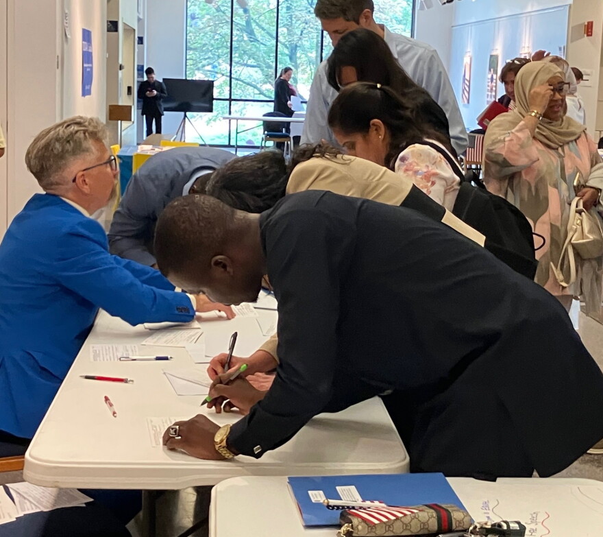 Augustana's Kai Swanson (left) signs up new citizens to register to vote in U.S. elections, after Tuesday's ceremony in the Centennial Hall lobby.
