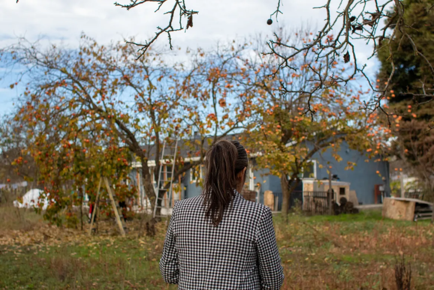 Juana Valle standing outside on her farm looking at her home.