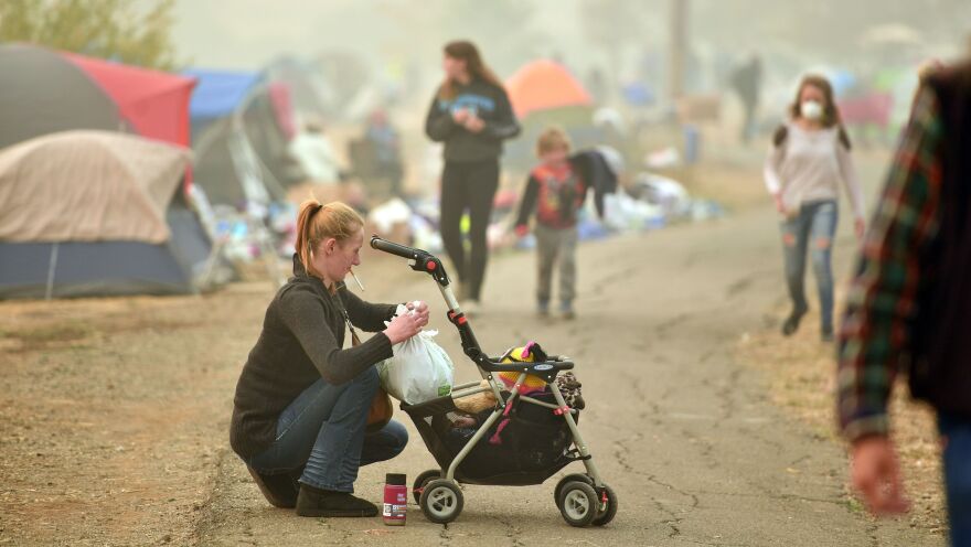 An evacuee tends to her baby Thursday at an encampment set up in a Walmart parking lot in Chico, Calif.