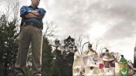 Detective Tim Robinson of the Warren County Sheriff's Office stands Monday beside HCL generators on Garrett Hollow Road after they were found in the woods at a meth dumpsite. Bowling Green-Warren County D