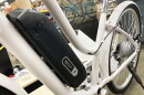 an electric motor sits along the frame of a white bicycle