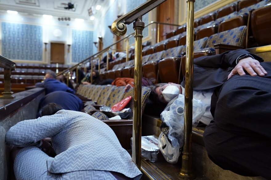 People shelter in the House gallery as protesters try to break into the House Chamber at the U.S. Capitol on Wednesday, Jan. 6, 2021, in Washington. (AP Photo/Andrew Harnik)