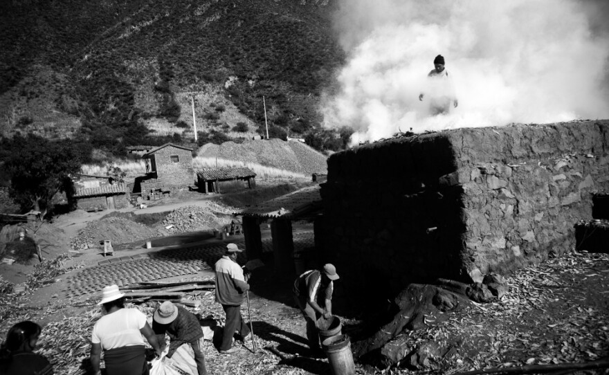 Carlos Apasa (in smoke) and his family tend to their traditional oven as they fire handmade roofing tiles in the village of Pinipampa. The village supplies tiles for construction projects throughout the Cusco department, and the highway has made transport much faster and easier.