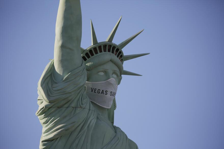 An oversized mask adorns the face of a replica Statue of Liberty at the New York-New York hotel and casino Thursday, July 16, 2020, in Las Vegas. MGM Resorts International has put a mask on the Statue of Liberty to remind people to wear a face-covering as a precaution against coronavirus.